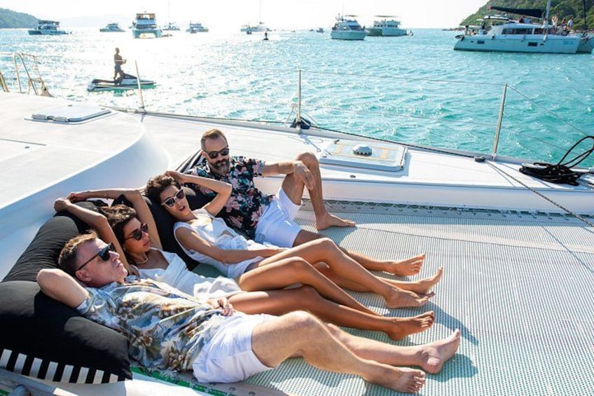 A group of people relaxing on a boat with a view of the sea and other boats in the background. 5