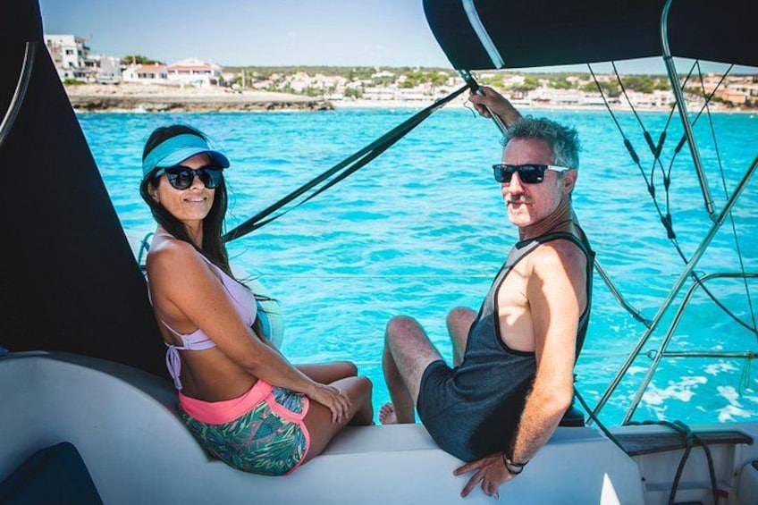 A couple on a sailboat with a coastal landscape in the background. 4