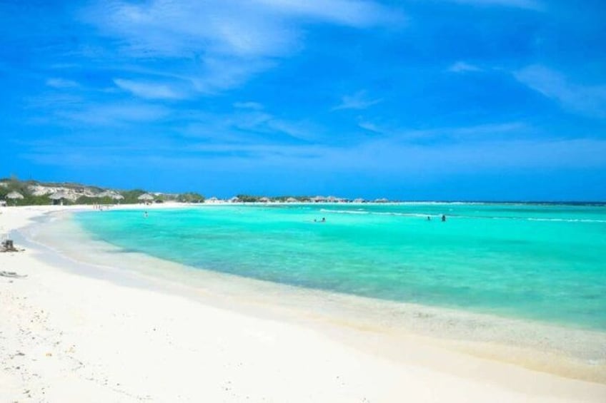 A beach with clear turquoise water and white sand. 1
