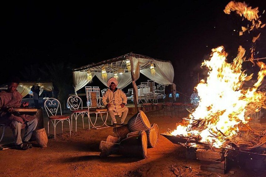 A person sitting on a chair near a campfire at night. 5