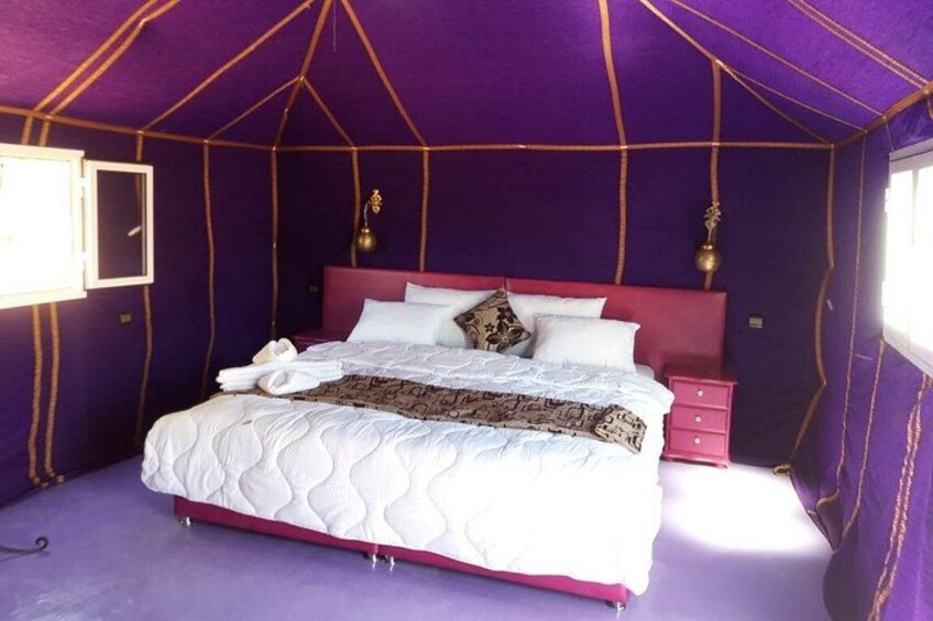 A tented room with a bed, pillows, and a nightstand. 4