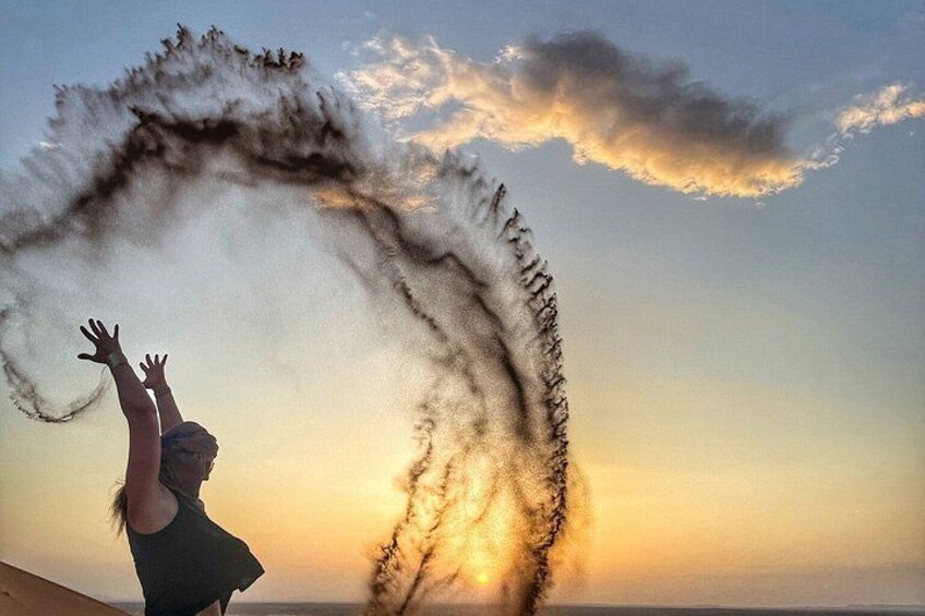 A person with arms raised, a sunset in the background, and a large dust or smoke cloud. 2