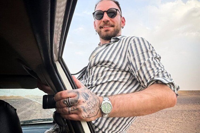 A person with tattoos holding onto a car door. 2