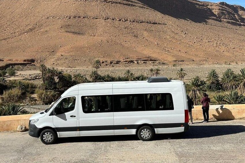A white van parked on a gravel road with palm trees and a desert landscape in the background. 3