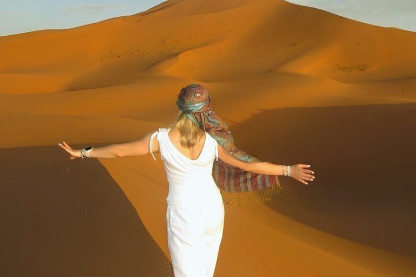 A person standing in a desert with sand dunes in the background. 1