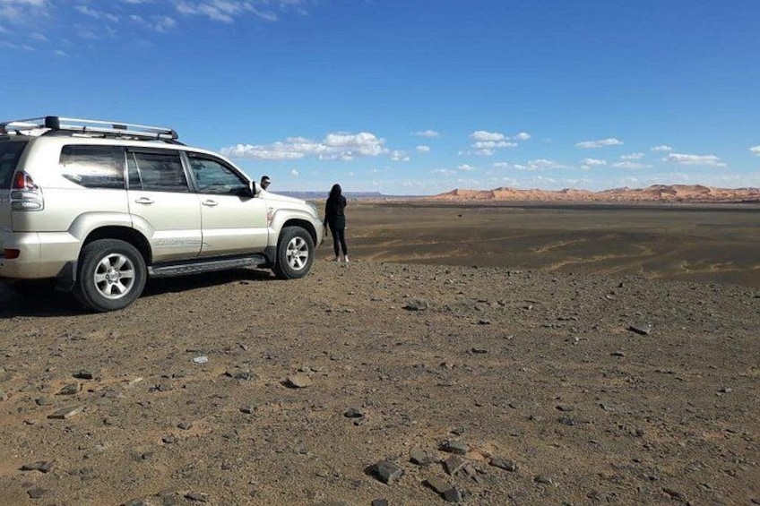 A white SUV parked on a rocky terrain with a person standing beside it. 5