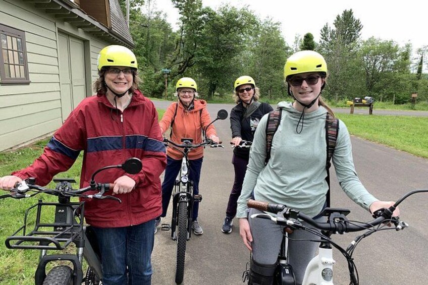 Four people on bicycles with helmets, wearing jackets, and carrying backpacks. 2