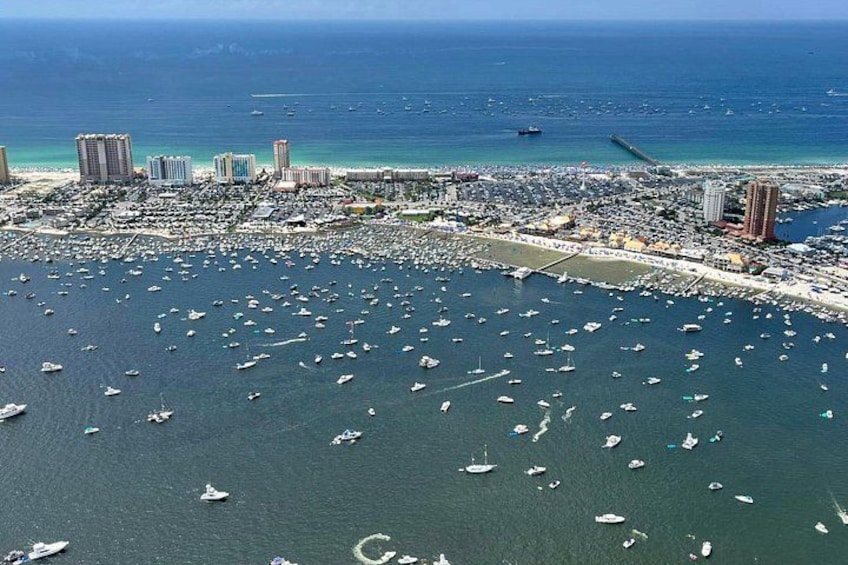 A coastal cityscape with numerous boats in the marina and a large body of water in the background. 3