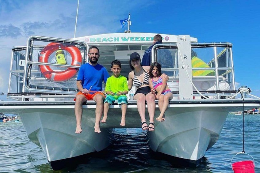 A boat with people sitting on the deck, a life preserver, and a flag. 1