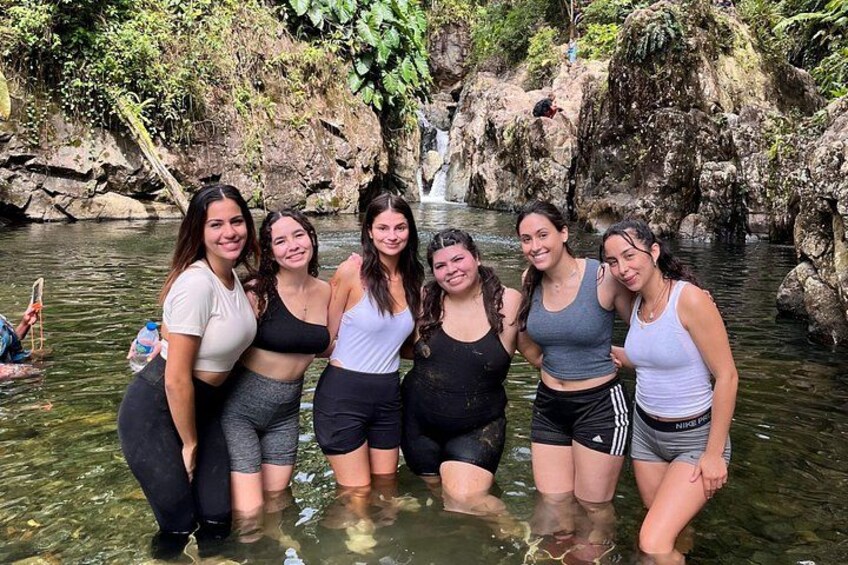A group of people standing in a river with a waterfall in the background. 2