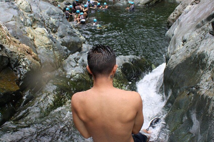 A person standing by a rocky water body with a waterfall. 3
