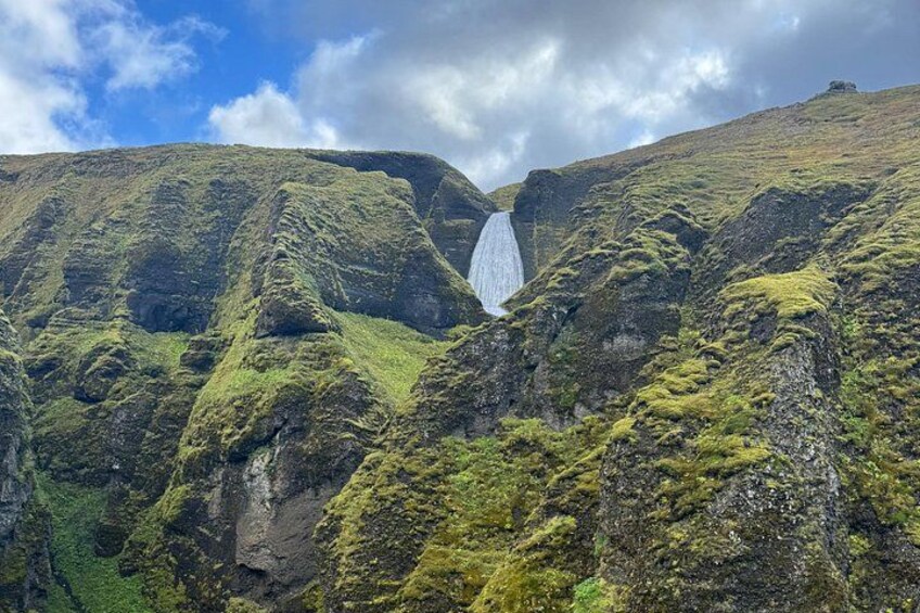 Een waterval stort naar beneden over een steile, met mos begroeide berg. 4