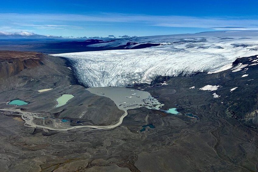 Un glaciar con un gran desprendimiento de hielo, un paisaje árido y varios lagos pequeños. 2