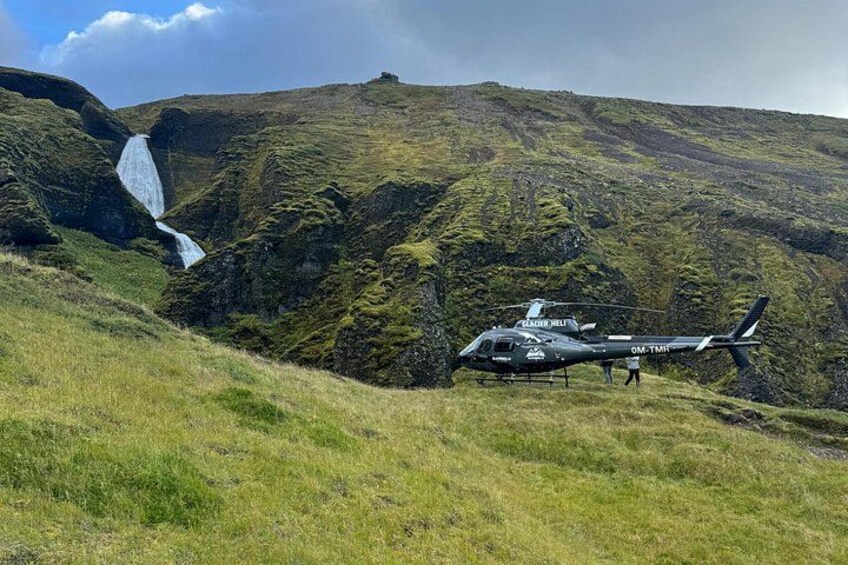 Een helikopter op een grasheuvel met een waterval op de achtergrond. 3