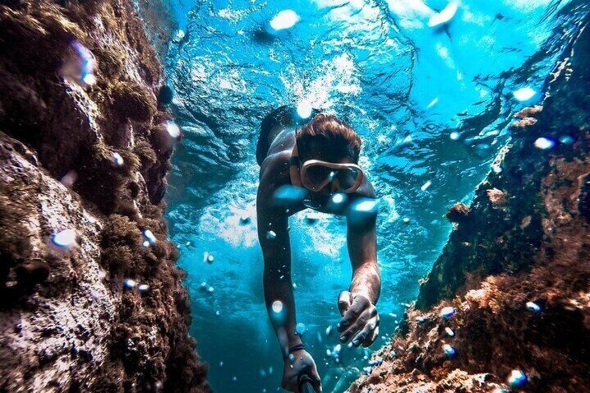En person snorkler under vand blandt klippefyldte omgivelser. 5