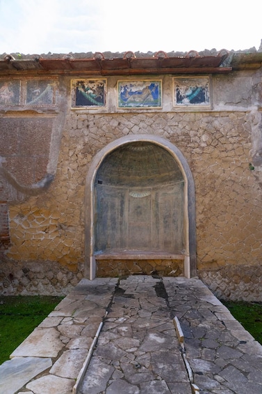 A stone wall with frescoes and an arched doorway. 2