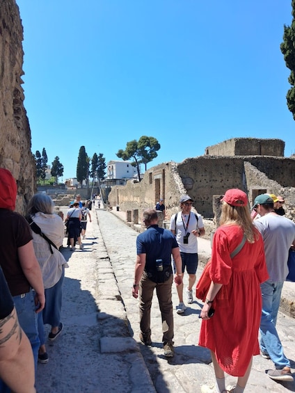 A group of people walking along an ancient stone pathway with ruins on either side. 3