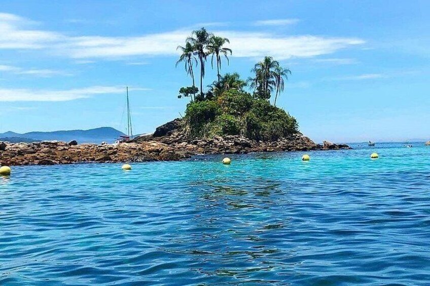A tropical island with clear blue waters, a small rocky outcrop, and palm trees. 4
