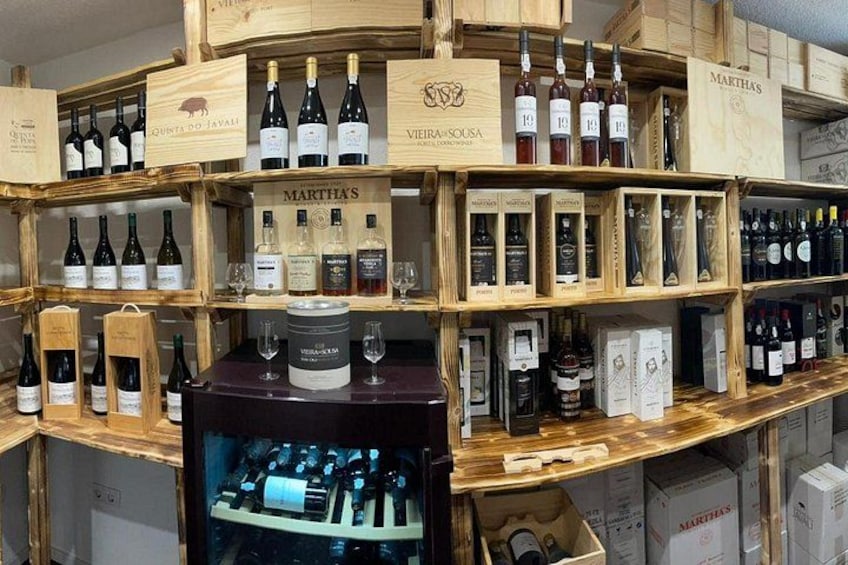 Una tienda de vinos con estantes de madera que exhiben diferentes botellas y cajas. 3