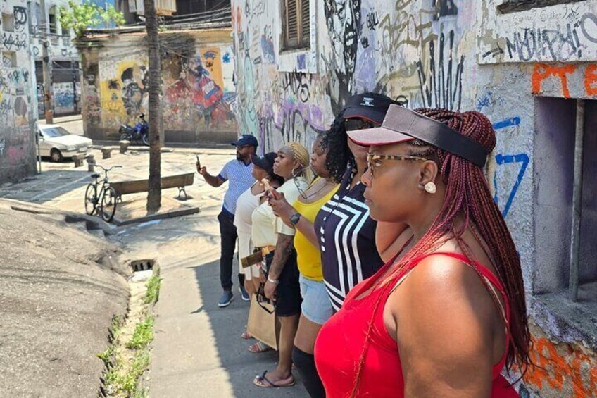 A group of people standing on a sidewalk in an urban area with graffiti on the walls. 4