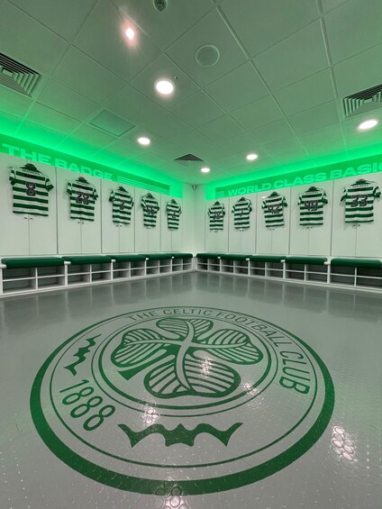 A sports hall with green lighting, a wall of jerseys, and a floor logo. 5