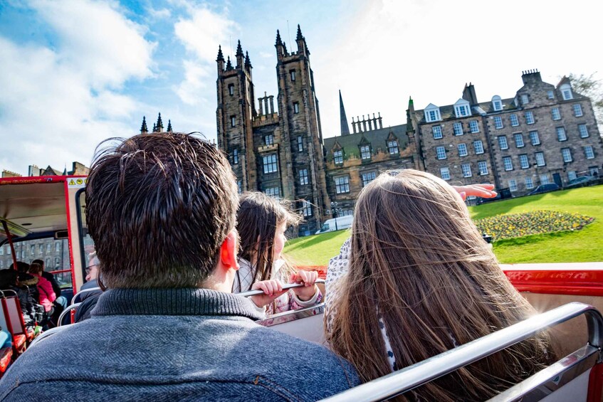 People on a tour bus looking at a historic building with towers. 3