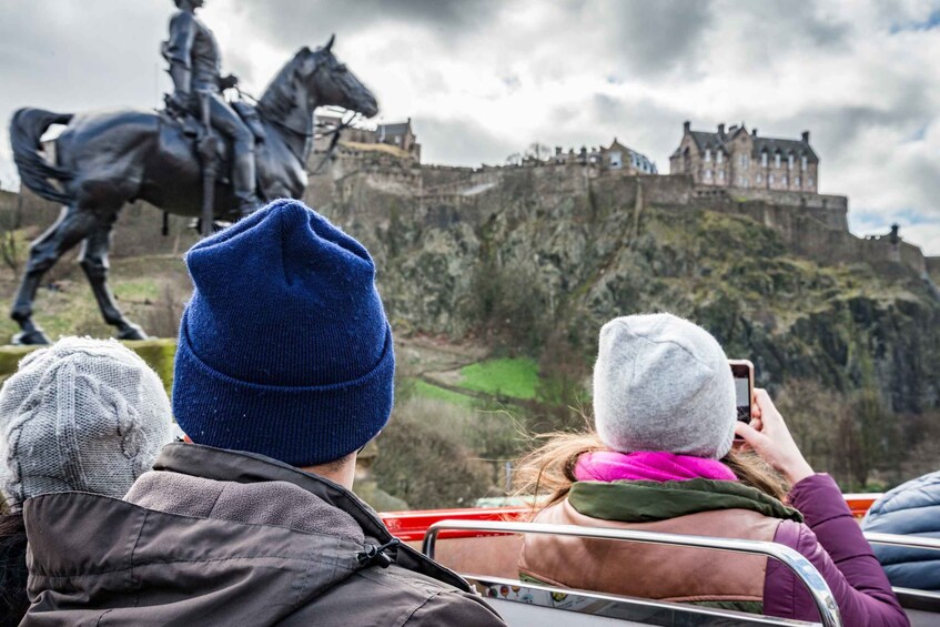 Tourists taking a photo of a statue of a man on horseback and a castle in the background. 1