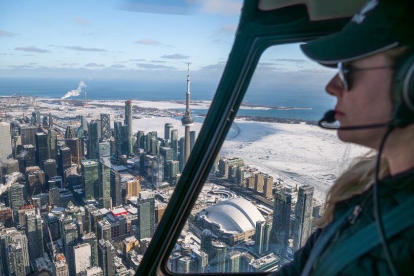 A helicopter view of a cityscape with skyscrapers, a stadium, and a body of water. 1