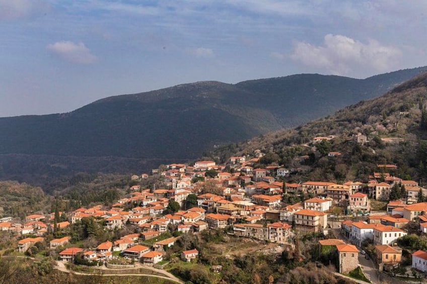 A hillside village with red-roofed houses and a mountainous backdrop. 2