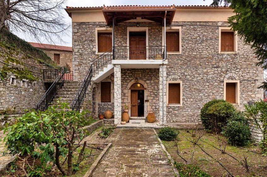 A stone building with a central entrance, a staircase, and a small garden area. 4