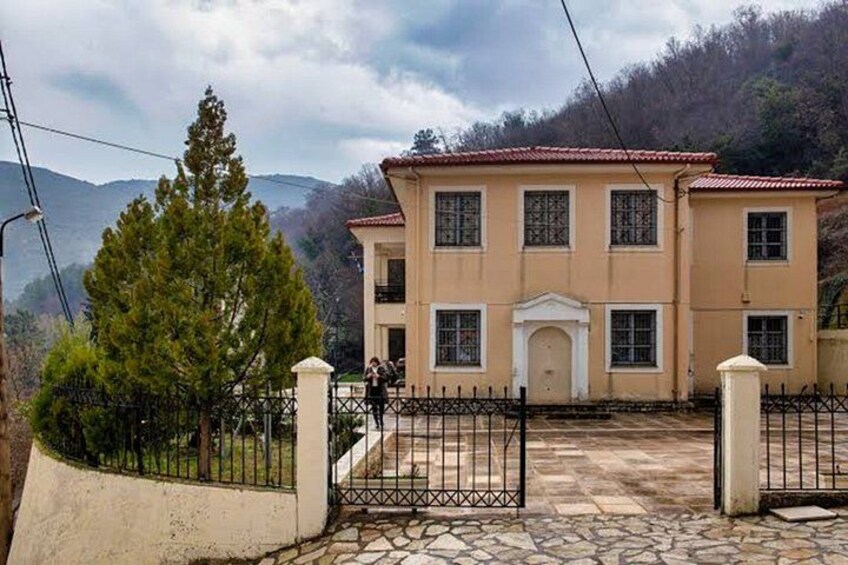 A two-story building with a tiled roof, a stone-paved entrance, and a metal fence. 3