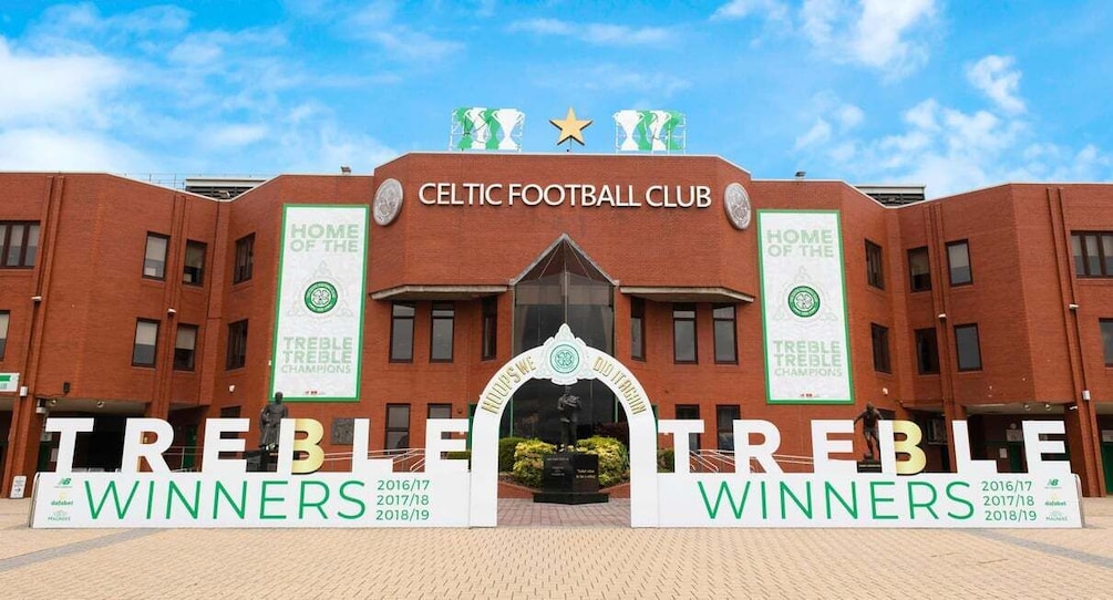 The Celtic Football Club entrance with banners for Treble Winners and a statue of a player. 2