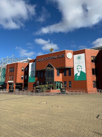 A building with a Celtic Football Club sign, a star on top, and a large green banner with a portrait. 5