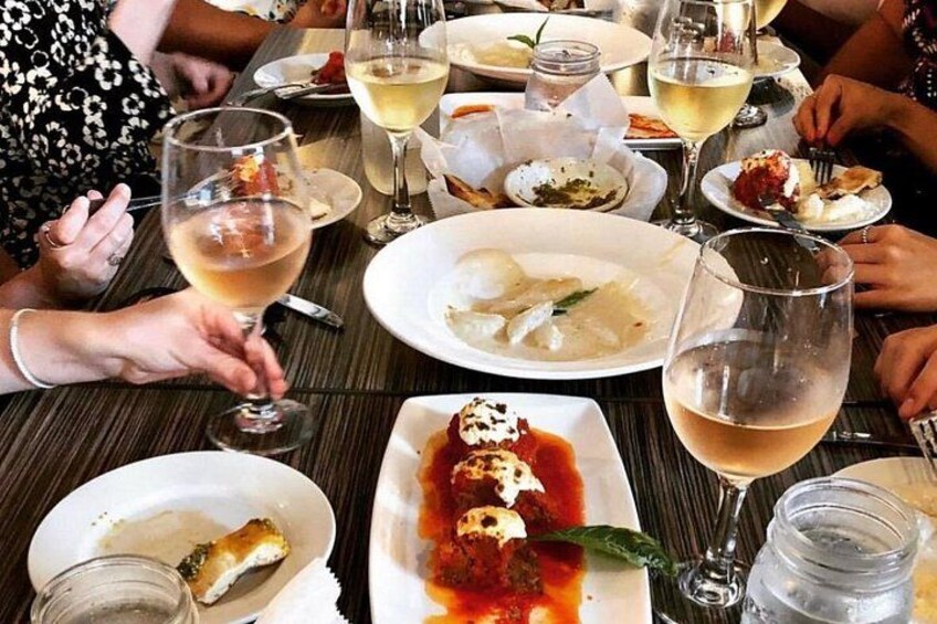 Una mesa de comedor con platos de comida, copas de vino y un tarro de agua. 4