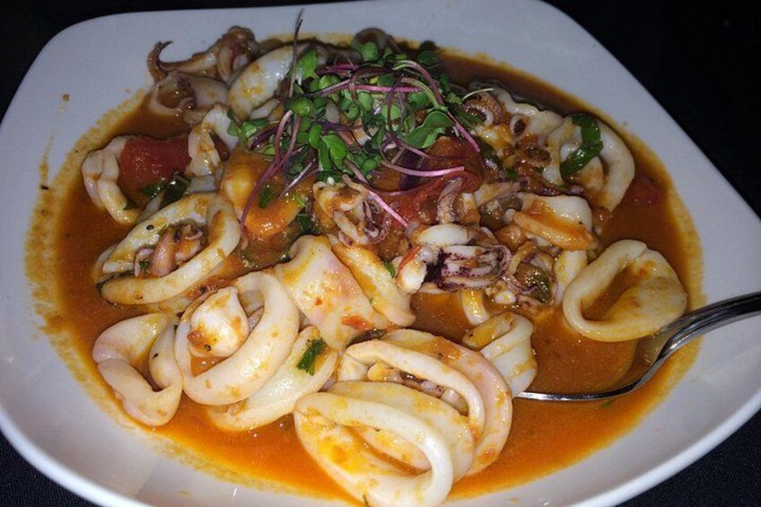 Un plato de pasta negra con un adorno de brotes tiernos y una cuchara. 2