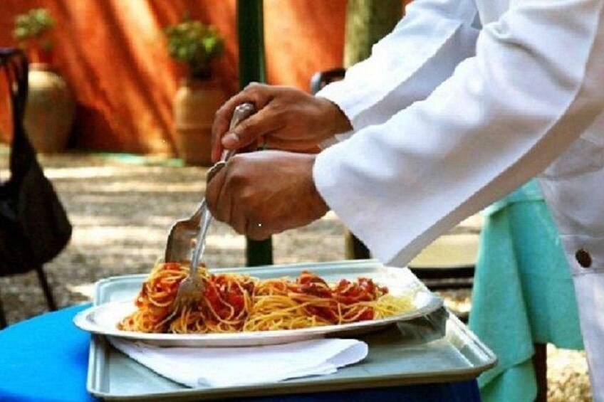 Una persona sirviendo espagueti en un plato. 1