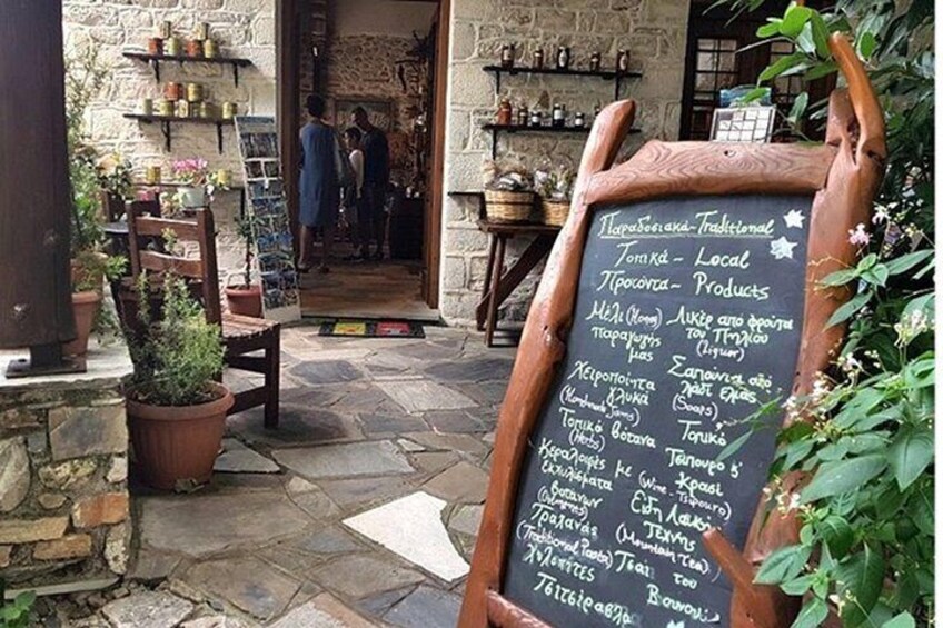 A rustic outdoor setting with a chalkboard menu listing local products and food items. 3