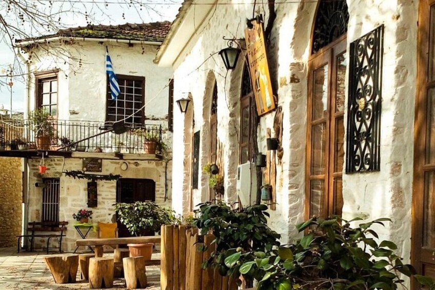 A traditional building with stone walls, wooden shutters, and potted plants. 1