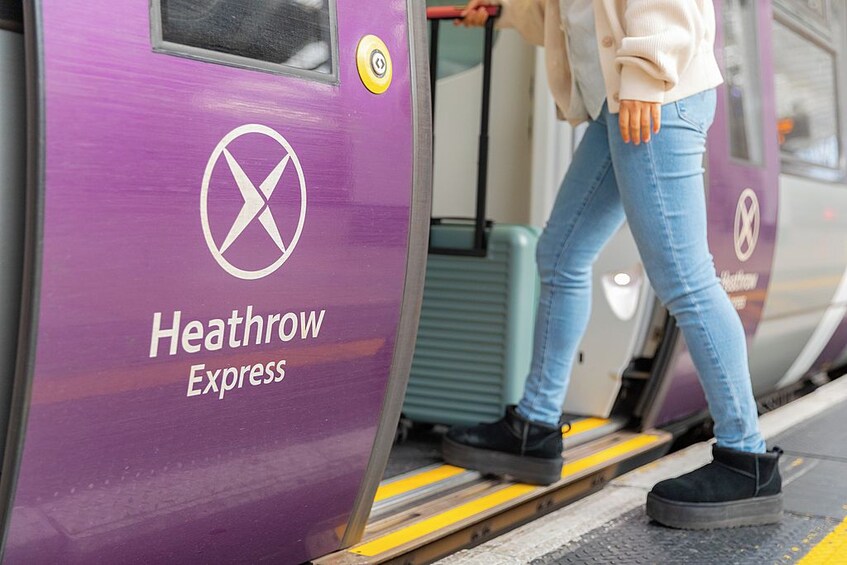Una persona sube a un tren púrpura con la inscripción 'Heathrow Express'. 4