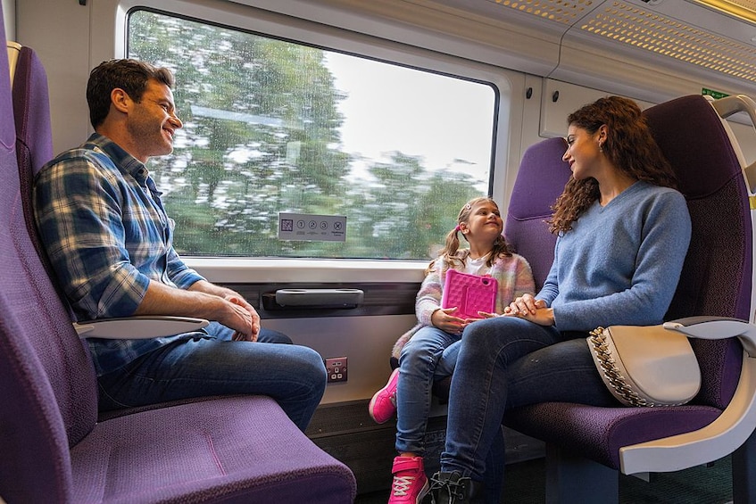 Interior de un tren con asientos morados, una ventana y una puerta. 3