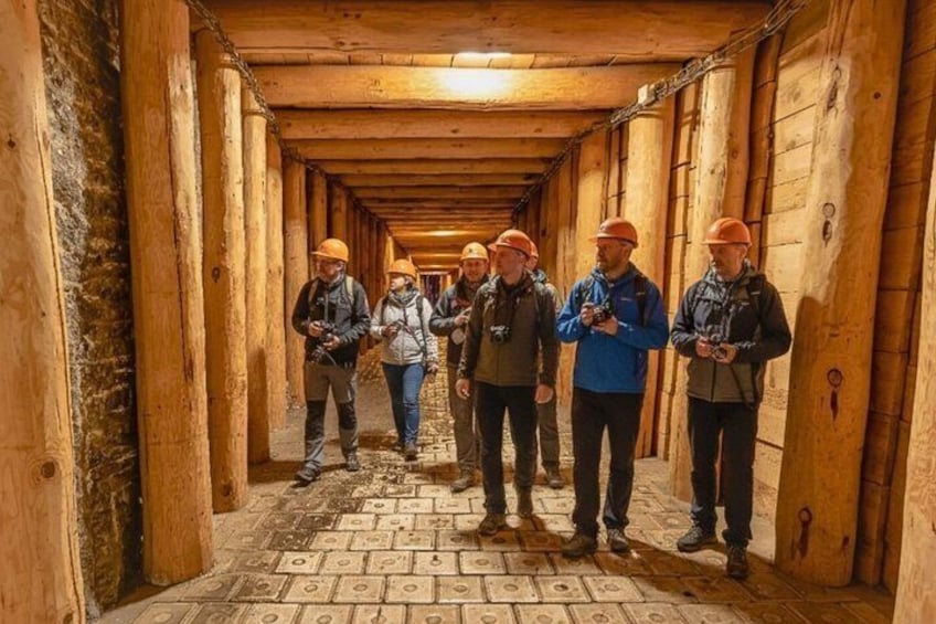 A group of people in a tunnel with wooden walls and patterned floor. 4