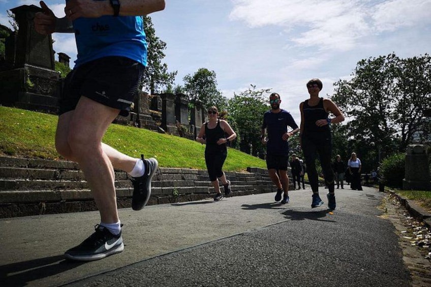 Des personnes font du jogging sur un chemin aménagé dans un parc, entouré d’herbe et d’arbres. 2
