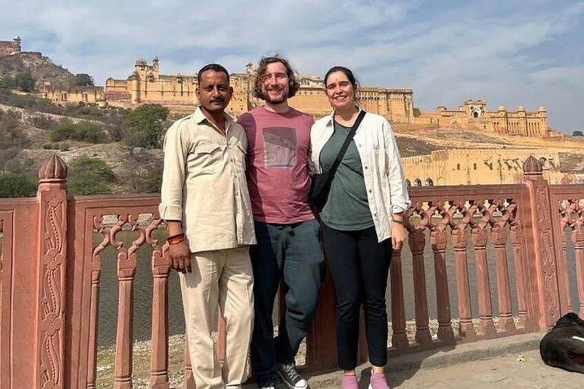 Three people standing on a bridge with a historic fort in the background. 4