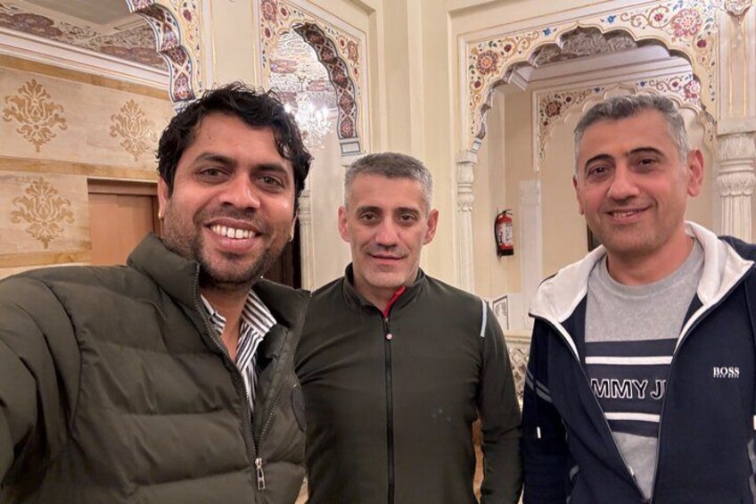 Three men standing in a room with ornate architectural details. 2