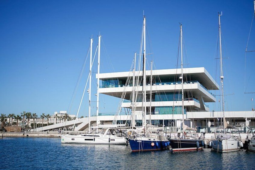 Een moderne jachthaven met verschillende zeilboten afgemeerd voor een modern gebouw. 4