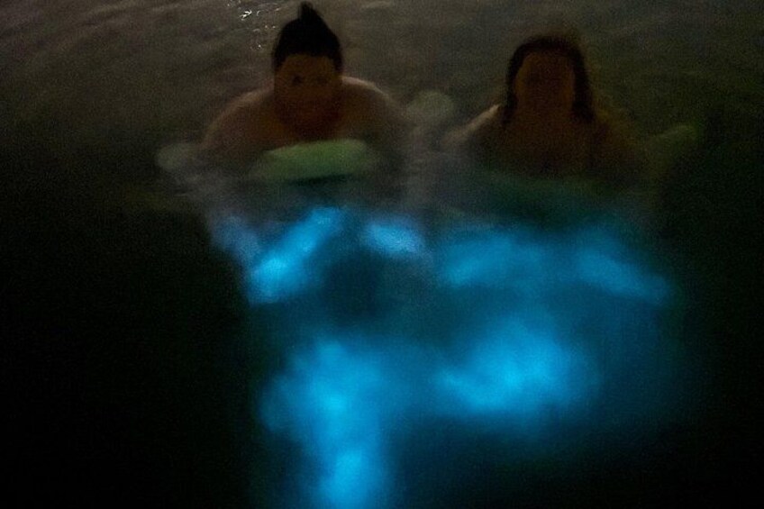 Dos personas en el agua, posiblemente una piscina o lago, con una fuente de luz azul. 4