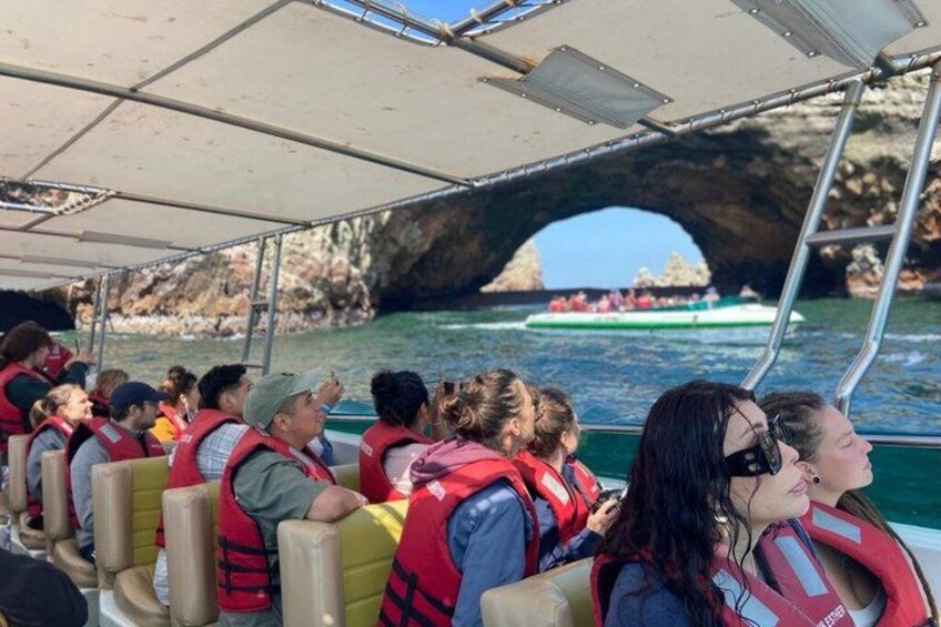 Personas en un bote, con chalecos salvavidas, y una costa rocosa con otro bote al fondo. 5