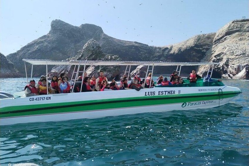 Un barco llamado 'Luis Esther II' con pasajeros que llevan chalecos salvavidas, navegando cerca de acantilados rocosos. 1
