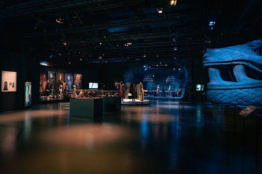 An indoor exhibition with a large dragon sculpture, display cases, and a stage with performers. 2