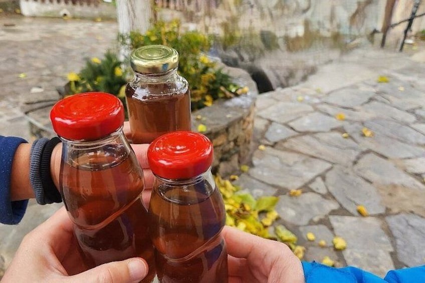 Una persona sosteniendo tres botellas de vidrio con tapones rojos. 5